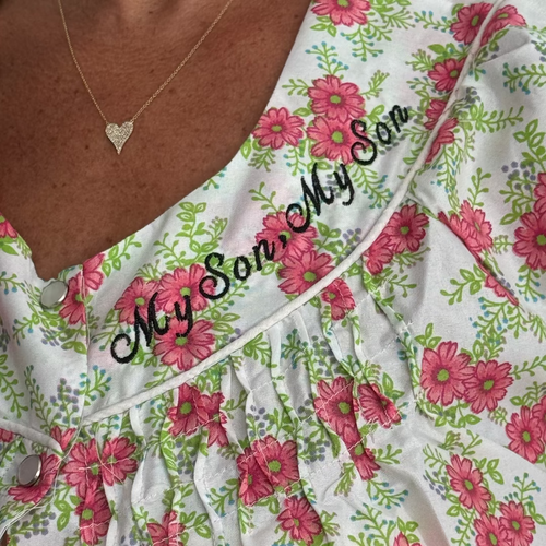 Close-up of a floral nightgown with pink flowers and green leaves on a white background, featuring the embroidered text 'My Son, My Son' across the chest.